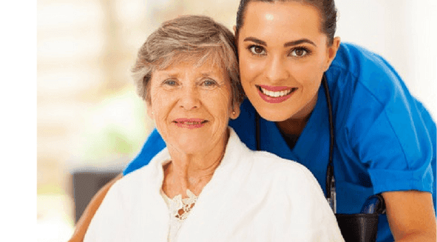 A caregiver poses with an elderly woman at the hospital